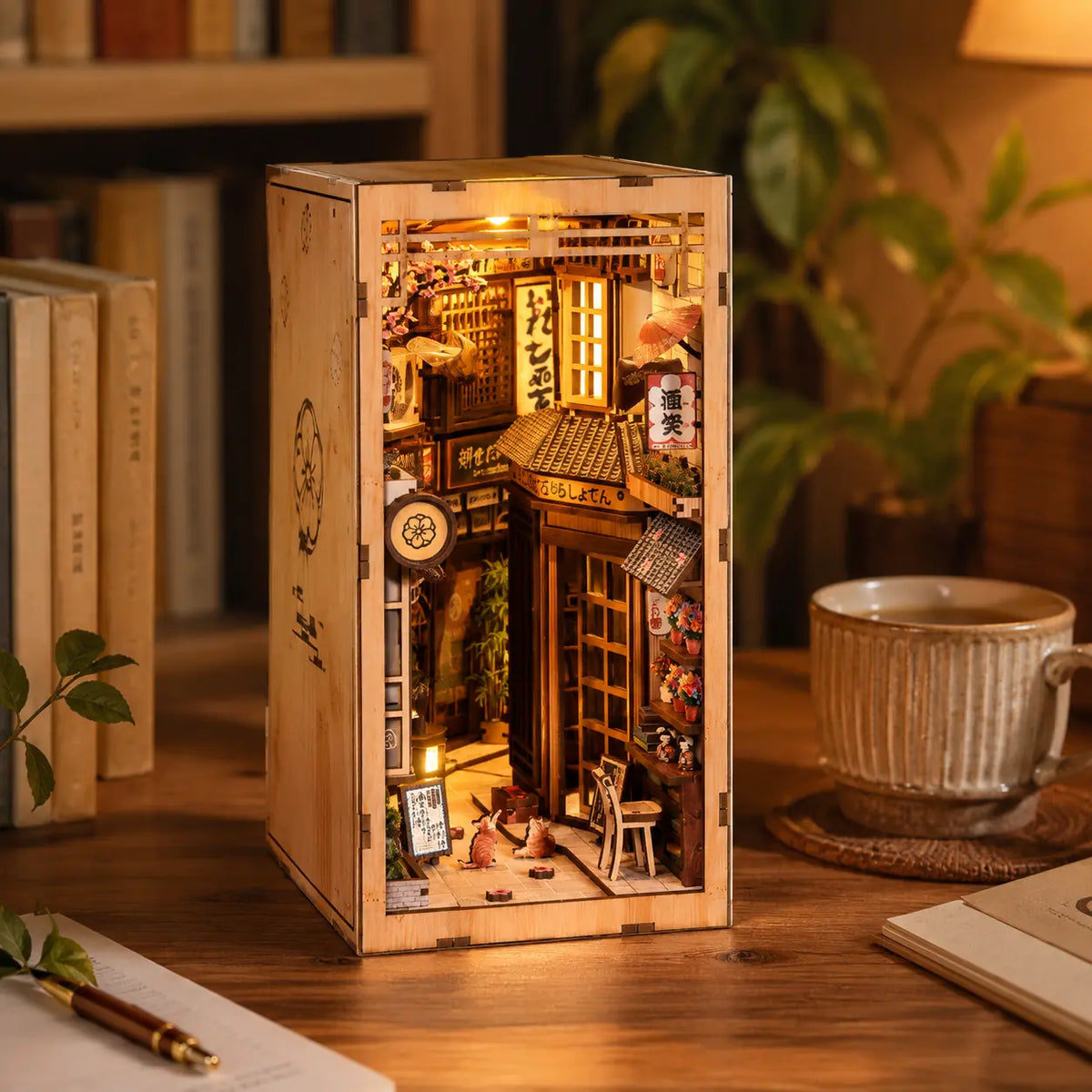 Book nook japonés iluminado sobre una mesa junto a libros