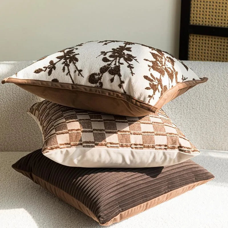Housse de coussin dans des tons bruns avec motifs de branches, de carreaux et des textures