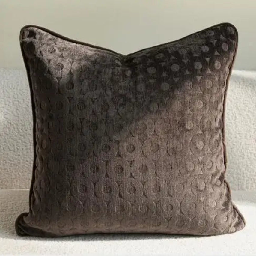 Housse de coussin dans des tons bruns avec motifs de branches, de carreaux et des textures