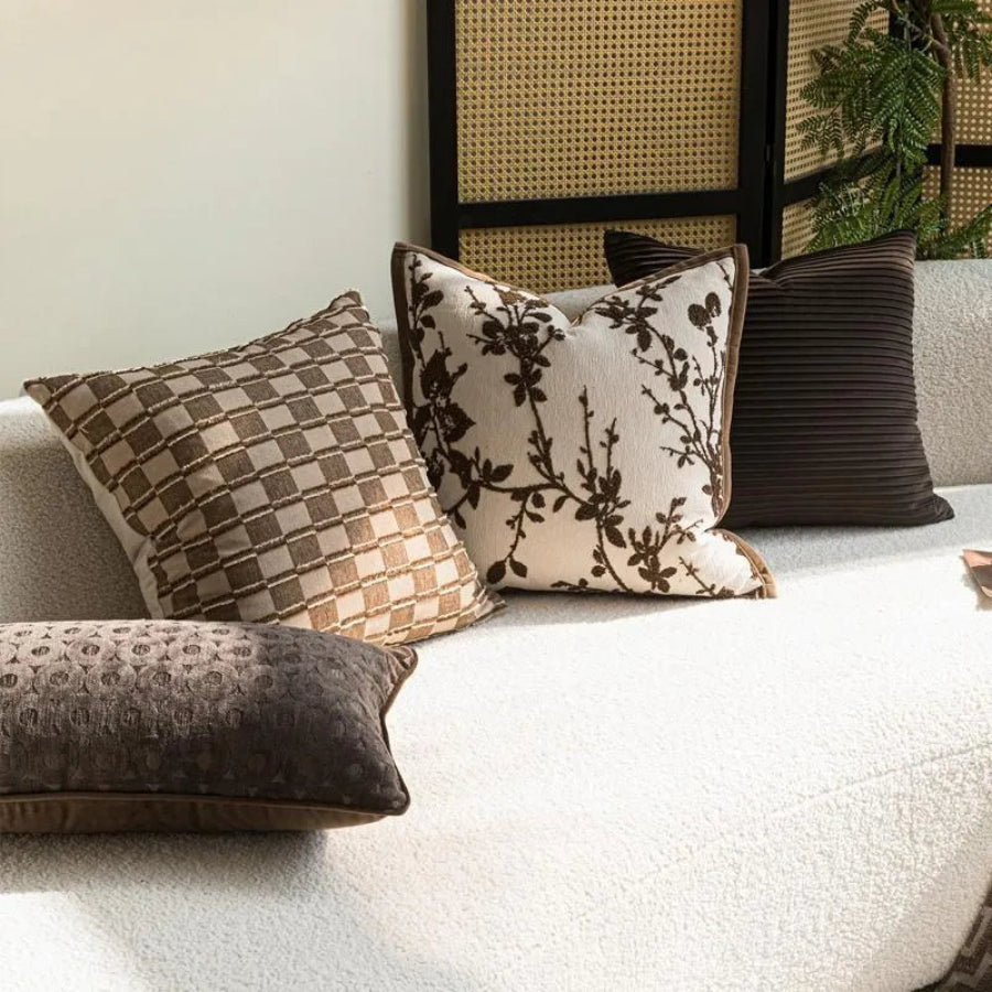 Housse de coussin dans des tons bruns avec motifs de branches, de carreaux et des textures