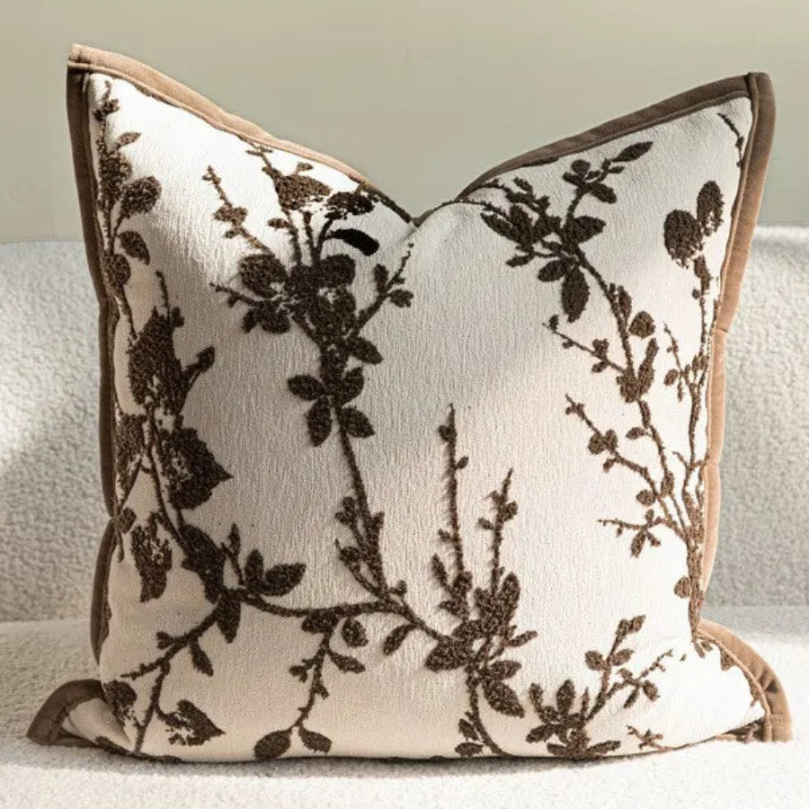 Housse de coussin dans des tons bruns avec motifs de branches, de carreaux et des textures