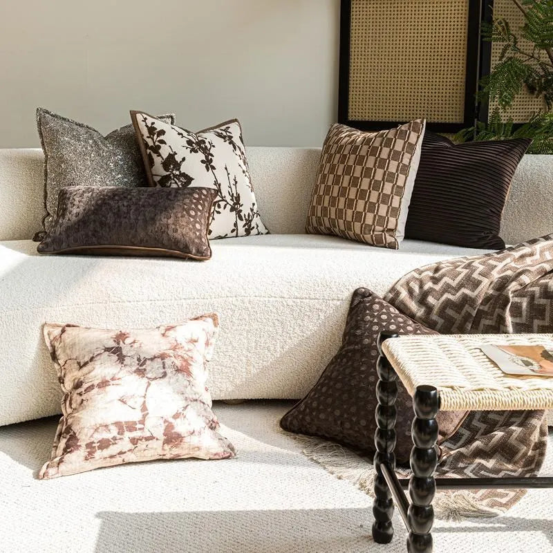 Housse de coussin dans des tons bruns avec motifs de branches, de carreaux et des textures
